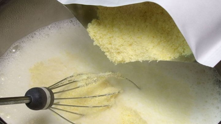 Ein Beutel mit Kartoffelp&uuml;ree wird &uuml;ber einem Topf geleert, w&auml;hrend ein Schneebesen im hei&szlig;en Wasser r&uuml;hrt.