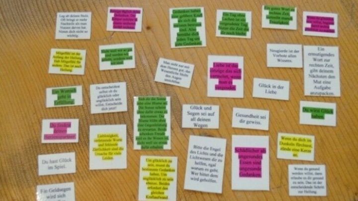 Bunte Zettel mit motivierenden Texten liegen auf einem Holztablett, um neuen Lebensmut zu vermitteln und Inspiration zu bieten.