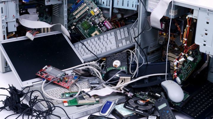 Ein Haufen alter Elektroger&auml;te, wie Computerteile und Handys, liegt chaotisch verteilt auf einem Tisch und verdeutlicht die Notwendigkeit zur richtigen Entsorgung.