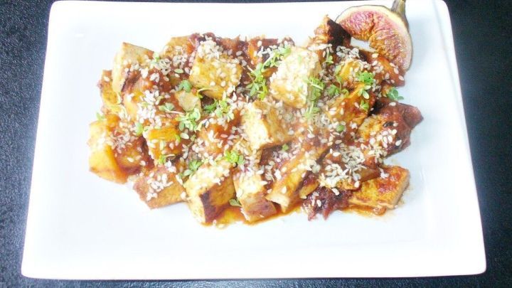 Gebratener, marinierter Tofu liegt auf einem wei&szlig;en Teller, umh&uuml;llt von fruchtiger Apfel-Feigenso&szlig;e und dekoriert mit Sesam.