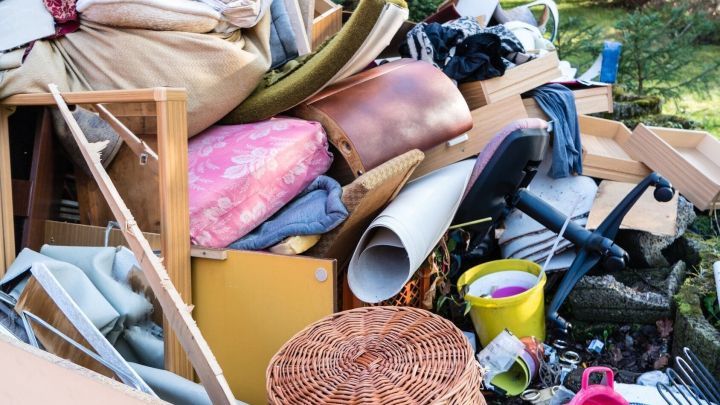 Eine gro&szlig;e Ansammlung von ger&auml;umten M&ouml;beln und Gegenst&auml;nden liegt im Freien, bereit zum Entr&uuml;mpeln und Aufr&auml;umen.