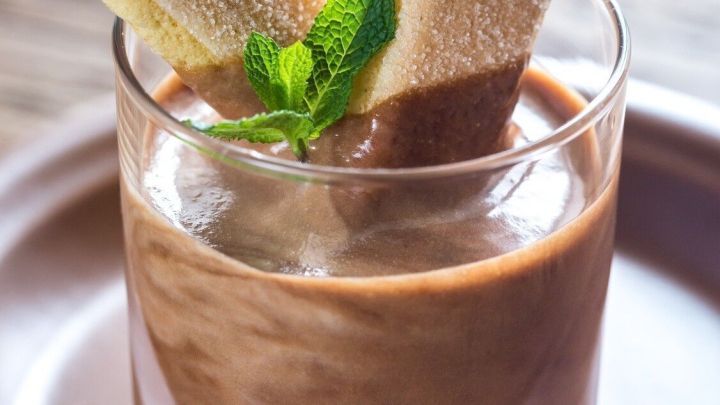 Ein Glas Blitzdessert mit cremigem Nutella und Mascarpone ist mit zwei Biskuits und frischer Minze dekoriert.