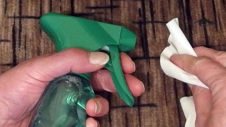 Eine Hand h&auml;lt einen gr&uuml;nen Spr&uuml;hreiniger, w&auml;hrend die andere ein Reinigungstuch f&uuml;r die Couch benutzt.