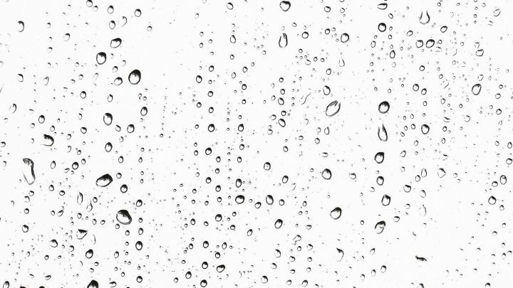 Wassertropfen haften an einem Fenster, w&auml;hrend sie bei Regen herunterlaufen und die Sicht obstruieren.