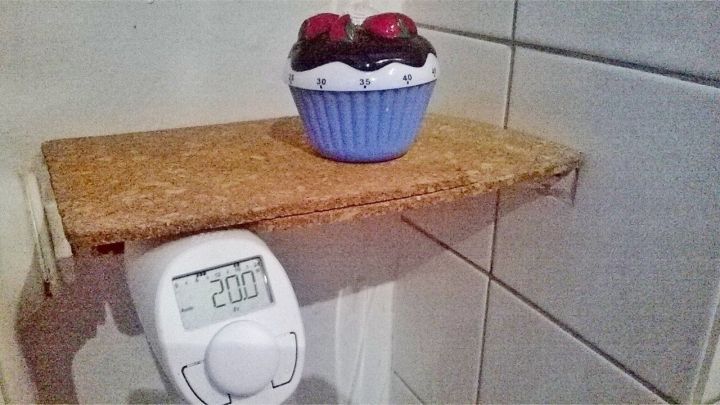 Ein Thermostat zeigt eine Temperatur von 20&deg;C, w&auml;hrend ein dekorativer Muffin auf einem kleinen Regal dar&uuml;ber steht.