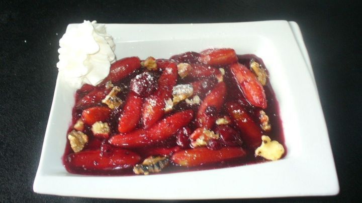 Auf einem wei&szlig;en Teller liegt eine Portion Rote Gr&uuml;tze, umrandet von Sahne, die frisch angerichtet wirkt.