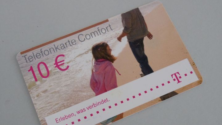Eine Telefonkarte im Wert von 10 &euro;, die Komfort bietet. Sie liegt auf einer glatten Oberfl&auml;che und zeigt ein Kind, das an der Hand eines Erwachsenen geht.