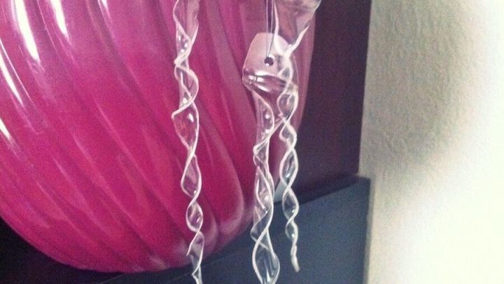 Dekorative Eiszapfen aus PET-Flaschen h&auml;ngen schwebend vor einer pinken Blumentopf, die die Pflanzen schm&uuml;ckt.