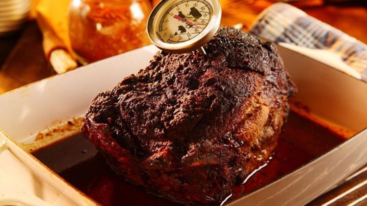 Ein saftiger Braten liegt in einer Schale, w&auml;hrend ein Thermometer die Temperatur beim Niedrigtemperaturgaren misst.