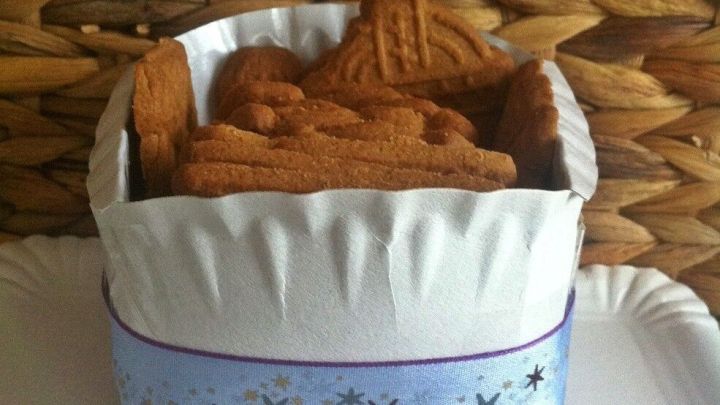 Ein kleiner Pappteller gef&uuml;llt mit Keksen steht auf einem wei&szlig;en Untergrund, umgeben von einer geflochtenen Wand aus Bast.