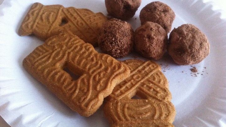 Die feinen Spekulatius-Tr&uuml;ffel liegen neben knusprigen Spekulatiuspl&auml;tzchen auf einem wei&szlig;en Pappteller.