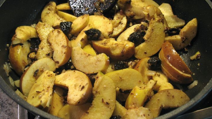 In einer Pfanne werden saftig gebratene Quitten und Backpflaumen zusammen gemischt, um ein k&ouml;stliches Gericht zu kreieren.