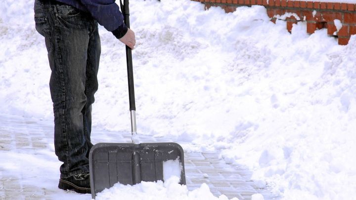 Ein Mann schaufelt Schnee von einem Gehweg, um ihn sicherer und umweltfreundlicher zu gestalten.