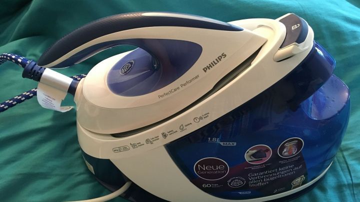 Eine Dampfb&uuml;gelstation von Philips steht auf einer gr&uuml;nen Oberfl&auml;che und bereit, Kleidung zu gl&auml;tten.