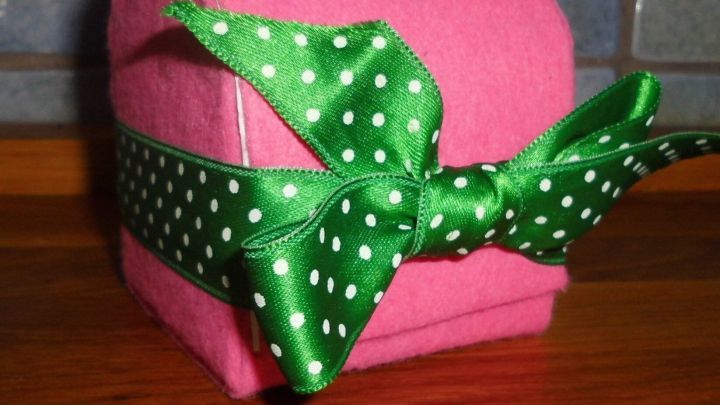 Eine pinke Geschenkschatulle aus Tetra Pak ist liebevoll mit einem gr&uuml;nen, gepunkteten Band verziert und steht auf einer Holzfl&auml;che.