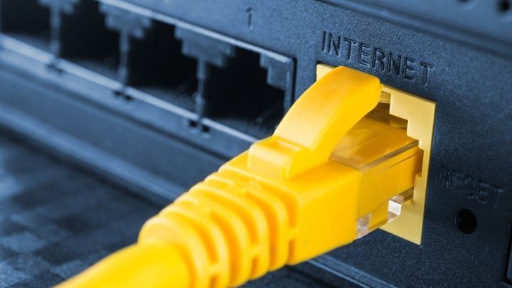 Ein gelbes Ethernet-Kabel ist mit einem Router verbunden, der das Internet bereitstellt, in einer modernen Wohnumgebung.