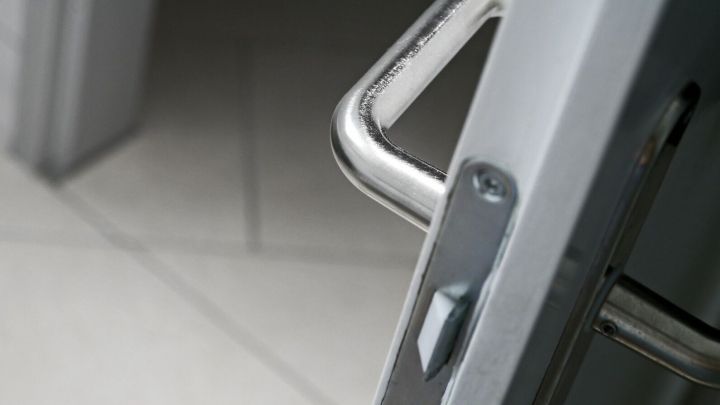 Ein silberner T&uuml;rgriff steht offen, w&auml;hrend sich die T&uuml;r in einem modernen, hellen Raum befindet.