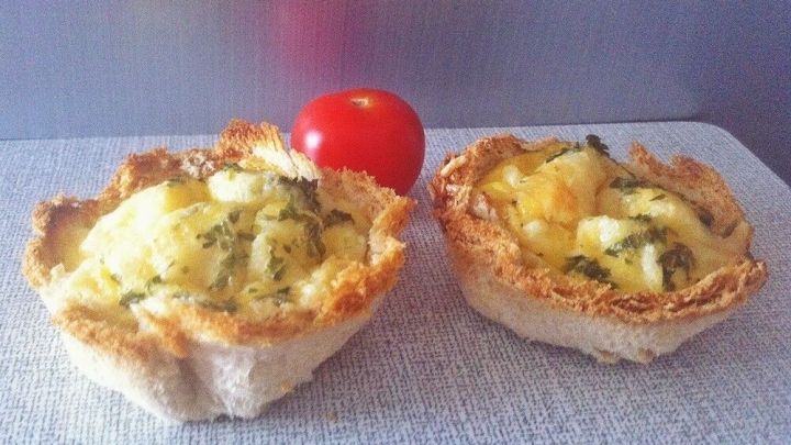Zwei Toast-Mini-Quiches stehen auf einem hellen Untergrund, ein roter Snack davor, umgeben von neutralem Hintergrund.