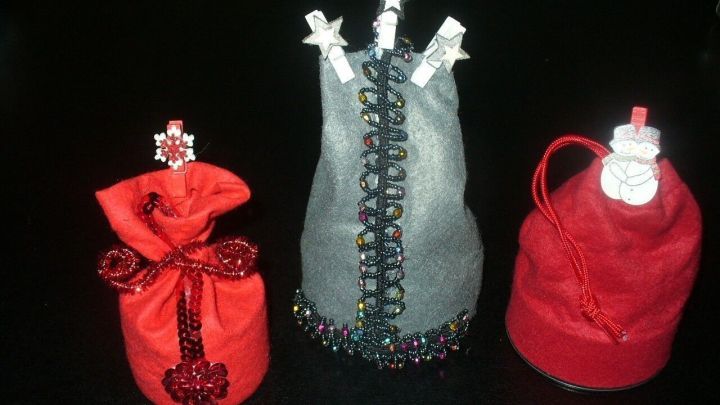 Drei bunte Geschenks&auml;ckchen aus Dosen stehen auf einem Tisch, jedes kreativ in unterschiedlichen Farben und Verzierungen gestaltet.