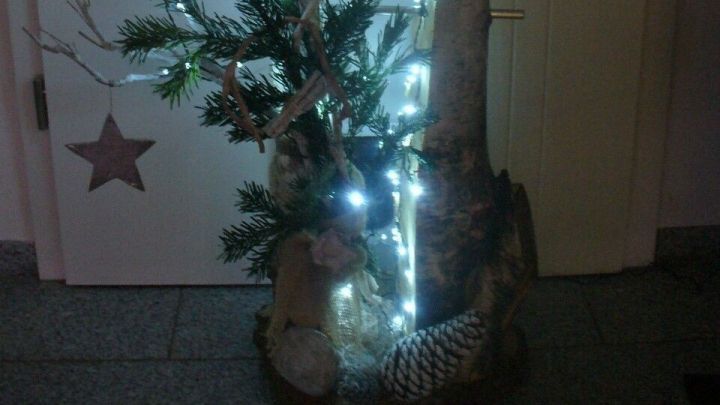 Eine kreative Au&szlig;endekoration aus Holz mit Lichtern und Zweigen, die festlich am Hauseingang leuchtet.