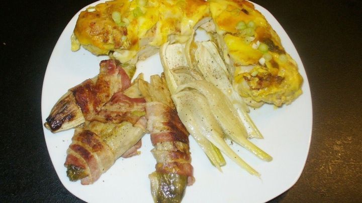 &Uuml;berbackene Mozzarella-H&auml;hnchenfilets sind auf einem wei&szlig;en Teller angerichtet, begleitet von geschmortem Chicoree.