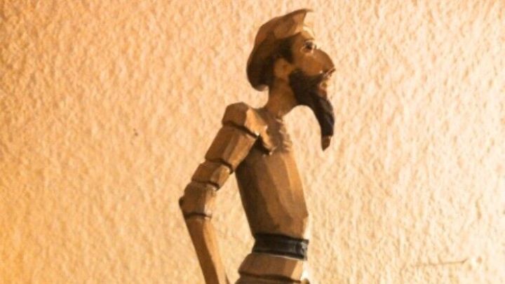 Eine h&ouml;lzerne Figur steht auf einem Tisch, als w&uuml;rde sie nachdenklich in die Ferne blicken, umgeben von einer neutralen Wand.