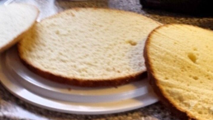 Drei geschnittene Tortenb&ouml;den liegen auf einem Dessertteller, w&auml;hrend eine Schneemann-Dekoration in der K&uuml;che steht.