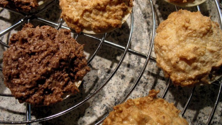 Kokosmakronen auf einem Kuchengitter, frisch gebacken, zeigen eine goldene und dunkle F&auml;rbung in einer gem&uuml;tlichen K&uuml;che.