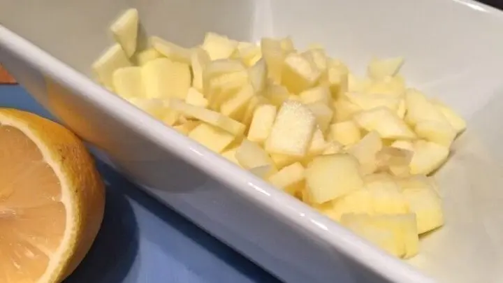 Den gesch&auml;lten Apfel in W&uuml;rfel schneiden und mit Zitronensaft vermischen.