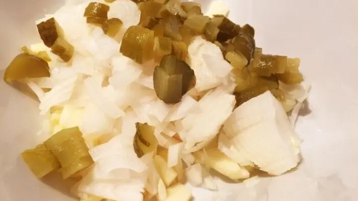 Gew&uuml;rzgurken und Zwiebel w&uuml;rfeln.