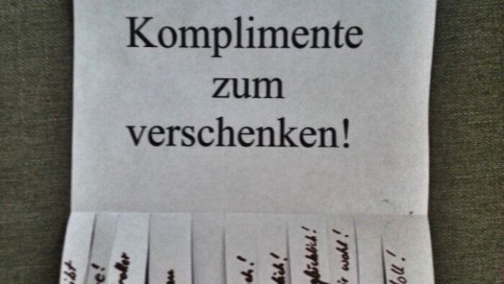 Eine gefaltete Papiernotiz zeigt die &Uuml;berschrift "Komplimente zum verschenken!" mit mehreren abgetrennten Komplimenten darunter.