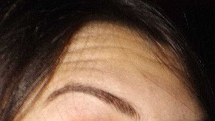 Ein gut gepflegtes Augenbrauen-Design ist sichtbar, w&auml;hrend eine Mascara-B&uuml;rste darauf angewendet wird, um Form zu schaffen.