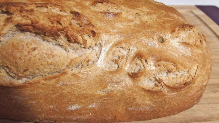 Ein Laib Brot liegt auf einem Holzbrett, mit einer leicht knusprigen Kruste, ideal zum Kaufen vom Vortag.