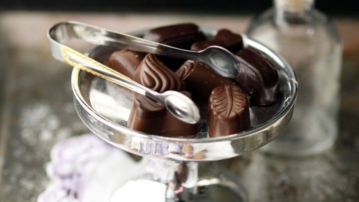 Ein eleganter Glasbeh&auml;lter steht auf einem Tisch, gef&uuml;llt mit Low Carb Pralinen und dekoriert mit einem L&ouml;ffel.