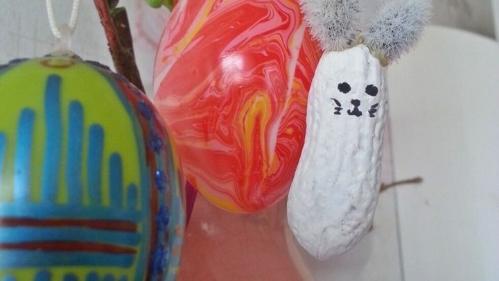 Bunte Erdnuss-Osterh&auml;schen und Eier h&auml;ngen an einem Strau&szlig;, um die fr&ouml;hliche Osterdeko zu pr&auml;sentieren.