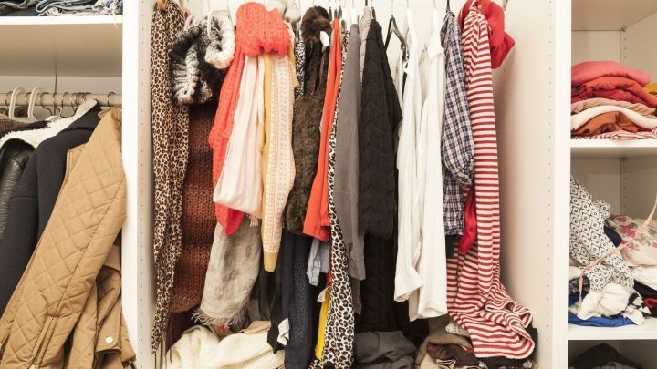 Eine bunte Auswahl an Winterkleidung h&auml;ngt ordentlich auf einem St&auml;nder, umgeben von unordentlich gefalteten Textilien.