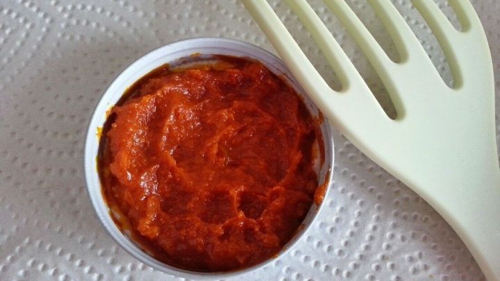 Eine kleine Schale mit BBQ-So&szlig;e steht auf einem K&uuml;chenpapier, daneben liegt ein spatelf&ouml;rmiger K&uuml;chenhelfer.