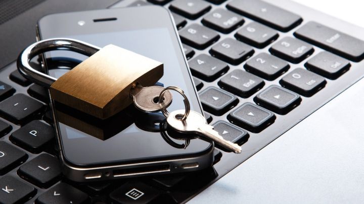Ein Smartphone liegt auf einer Laptop-Tastatur, darauf ein Schloss und ein Schl&uuml;ssel, die f&uuml;r ein sicheres Passwort stehen.