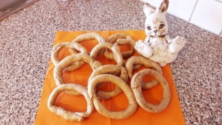 Die Fastenbeugerl liegen auf einem orangefarbenen Tuch, w&auml;hrend eine porzellanene Figur daneben sitzt.