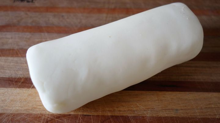 Eine wei&szlig;e Modelliermasse liegt auf einem Holzbrett, bereit zum Formen und Gestalten in kreativen Projekten.