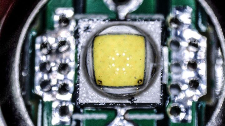 Ein gelbes LED-Licht leuchtet hell auf einem kleinen, metallischen Schaltkreis, umgeben von elektrischen Komponenten.