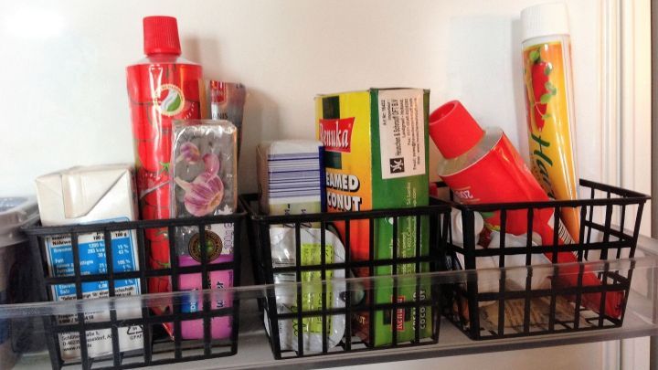 Kleine schwarze K&ouml;rbchen halten verschiedene Lebensmittel ordentlich im K&uuml;hlschrank, um &Uuml;bersichtlichkeit und Ordnung zu schaffen.
