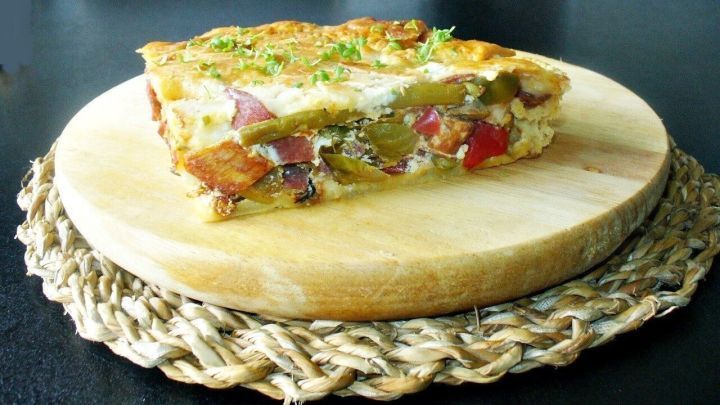 Eine saftige Zucchini-Tarte liegt auf einem Holzbrett, umgeben von einer nat&uuml;rlichen, rustikalen Unterlage.