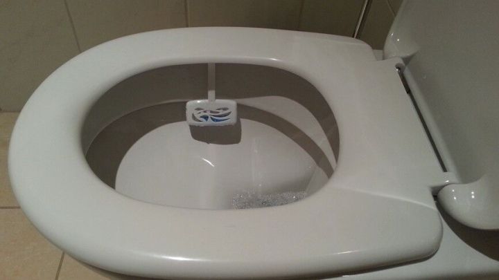 Eine Toilette mit einer speziellen Tab-Halterung zur Reinigung, sichtbar in einem modernen Badezimmer.