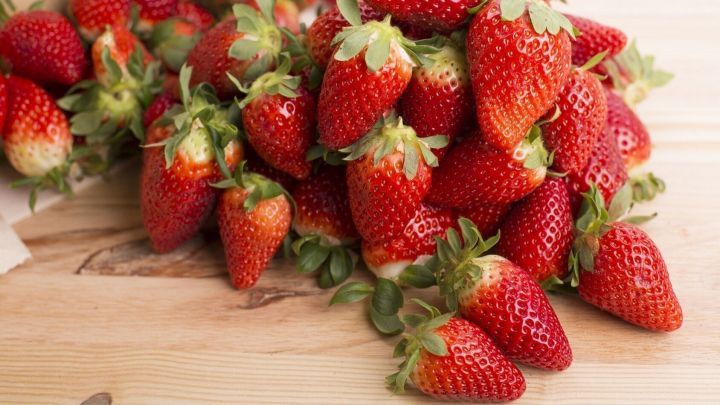 Saftige Erdbeeren liegen auf einer rustikalen Holzoberfl&auml;che, die f&uuml;r m&ouml;gliche Obstflecken auf Naturholzm&ouml;beln empfindlich ist.