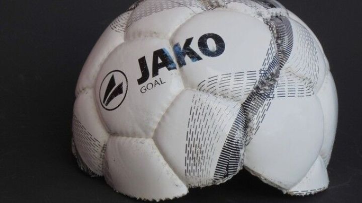 Ein alter Fu&szlig;ball liegt auf einem schwarzen Hintergrund und zeigt Gebrauchsspuren, was M&ouml;glichkeiten zur Wiederverwendung anregt.