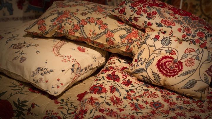 Bunte Bettw&auml;sche und Kissen sind kunstvoll gestapelt und verleihen einem gem&uuml;tlichen Raum W&auml;rme und Stil.