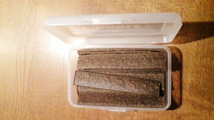 Ein Container mit unangenehm riechenden Hundeleckerli steht auf einem Holzuntergrund, ge&ouml;ffnet und sichtbar.