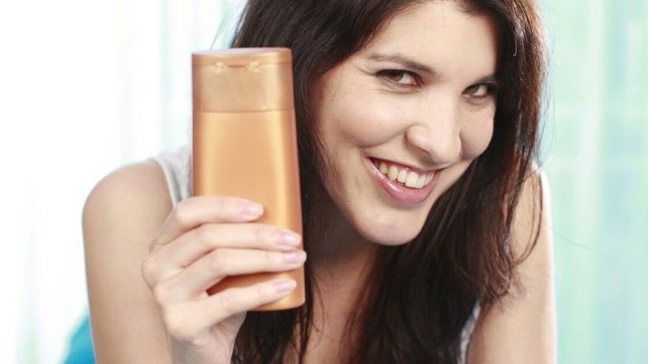 Eine l&auml;chelnde Frau h&auml;lt einen Selbstbr&auml;uner in einer hellen Umgebung, umgeben von einem blauen Tuch und einer Bl&uuml;te.