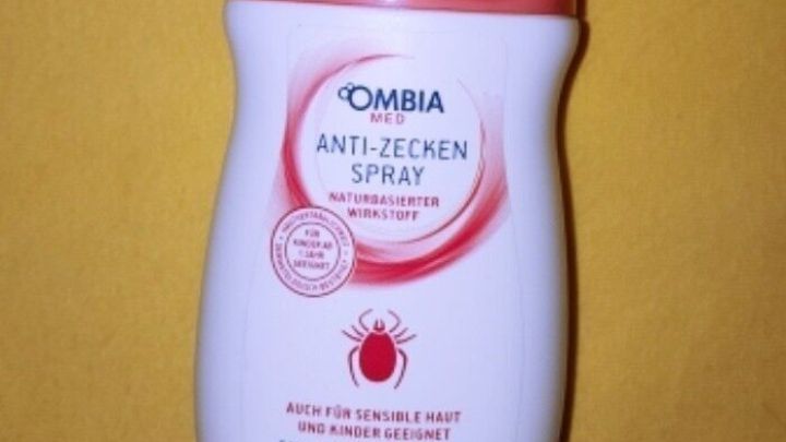 Ein Anti-Zecken-Spray in einer wei&szlig;en Flasche mit rotem Deckel steht auf einem gelben Hintergrund.